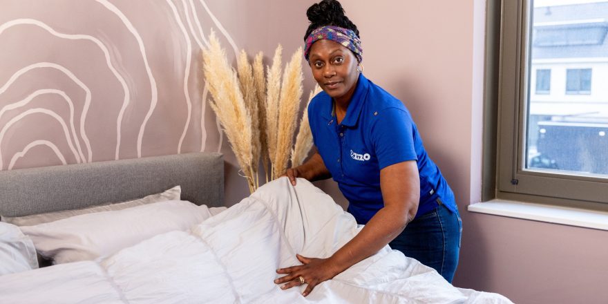 Schoonmaakmedewerker van Zizo maakt een bed op