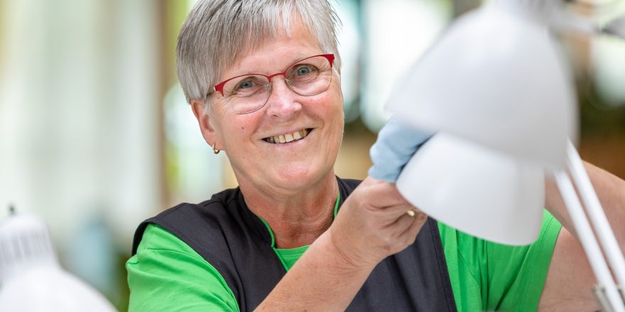 Schoonmaakmedewerker poetst lamp